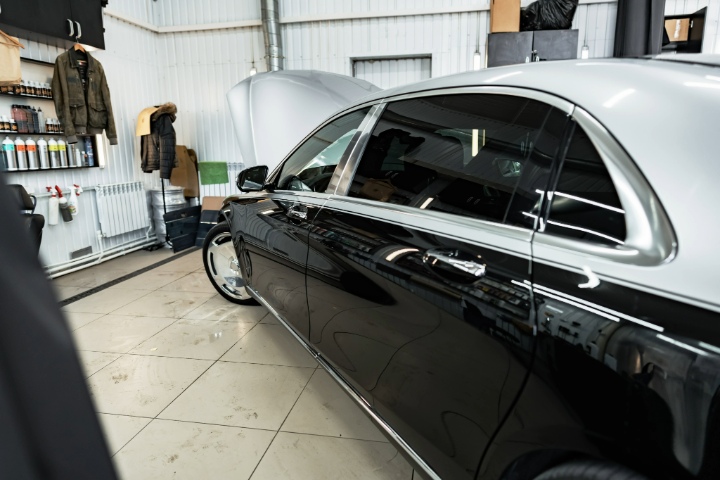 Luxury car with dark tinted windows parked inside auto detailing garage