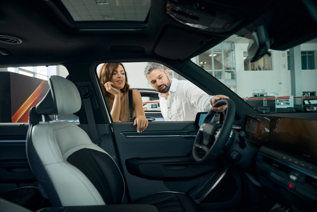Couple inspecting window tint on SUV at dealership showroom