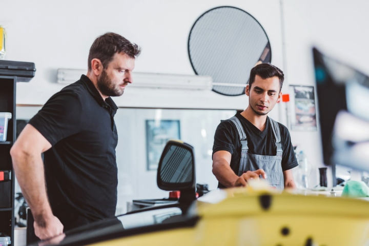 Window Tint Technician Explaining Film Options To Customer Inside A Tint Shop
